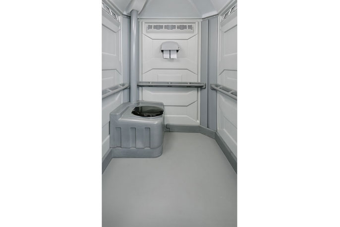 Innenraum einer grauen mobilen Toilette mit integriertem Sitz, Haltegriff und Toilettenpapierhalter an der Wand